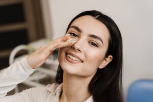 Woman smiling and touching her nose after liquid rhinoplasty in Los Altos, CA